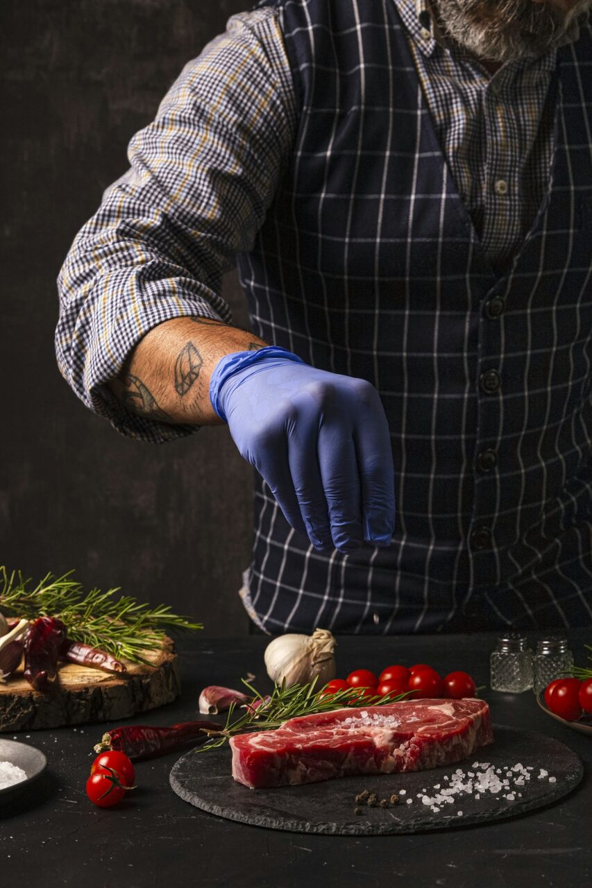 The chef brushes salt over the ready-to-grill beef entrecote
